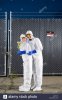 people-in-biohazard-suits-standing-outside-security-gate-AWP1T5.jpg