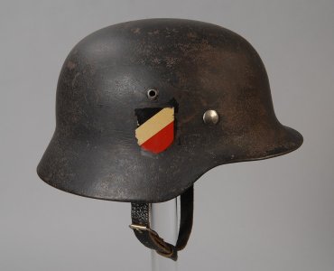 1280px-Duitse_militaire_Stahlhelm_M.35,_grijsgroen_met_rijkswapen,_leren_binnenhelm_en_kinrie...jpeg